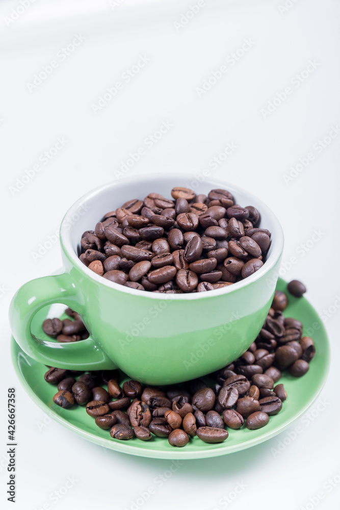 cup of coffee, close-up of a green ceramic cup with white inside, on a plate with coffee beans on a white surface, vertical photo cup of coffee, close-up of a green ceramic cup with white inside, on a plate with coffee beans on a white surface, vertical photo