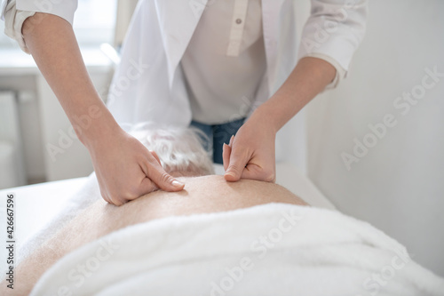 Massage therapist working with an elderly male patient