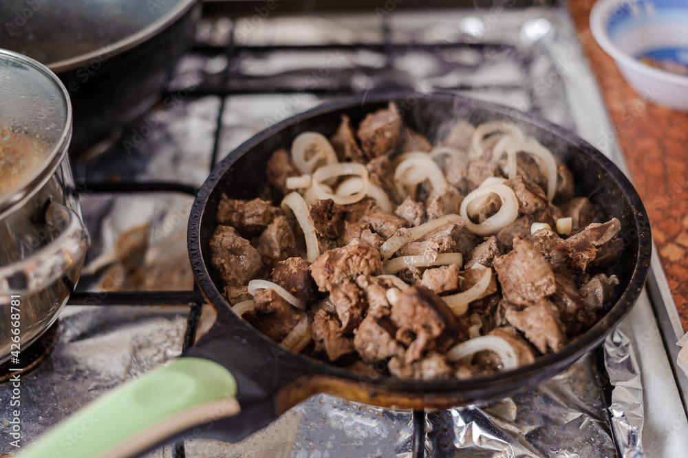 Fototapeta premium Fried veal liver with onions in a pan. Braised cow and pork liver