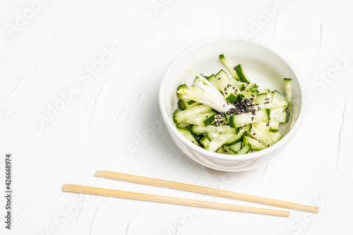 Fresh cucumber salad with sesame seeds in a white ceramic bowl