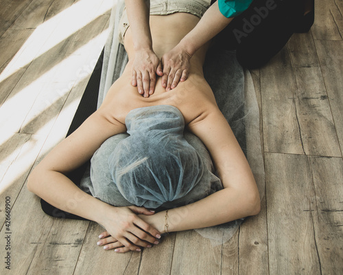 Unrecognizable Woman having Shiatsu massage by professional on wooden floor at salon