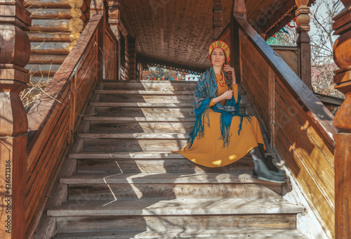 Russian beauty closeup is sitting on the stairs of wooden house in the village © volhavasilevich