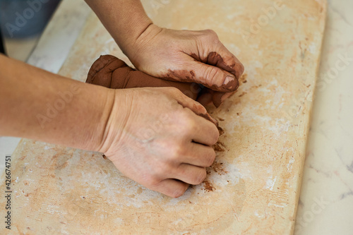 female hands of the master knead red clay. Preparation for work in the potter's workshop.