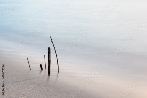 long exposure of wooden sticks sticking out of the water on the beach