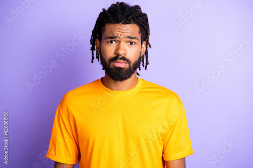 Photo of sad nice brunet man wear yellow t-shirt isolated on purple color background © deagreez
