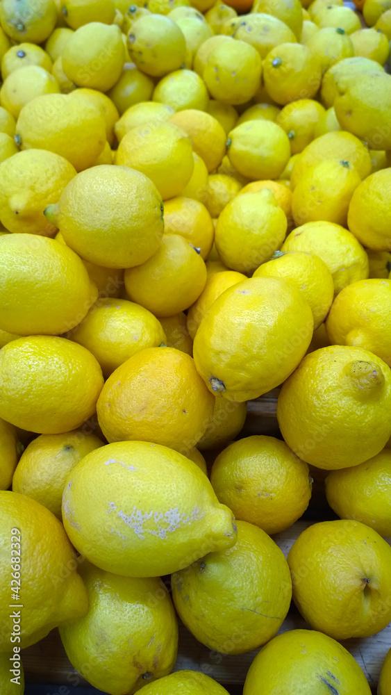 Yellow fresh lemons background. Fruits on supermarket shelves. Farmers market. Retail industry. Discount. Grocery shopping. Healthy eating. Greengrocer. Natural food. Store. Vertical view. Citrus Yellow fresh lemons background. Fruits on supermarket shelves. Farmers market. Retail industry. Discount. Grocery shopping. Healthy eating. Greengrocer. Natural food. Store. Vertical view. Citrus