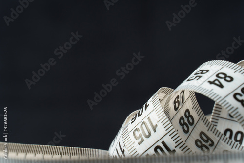 white centimeter tape on black background, close-up