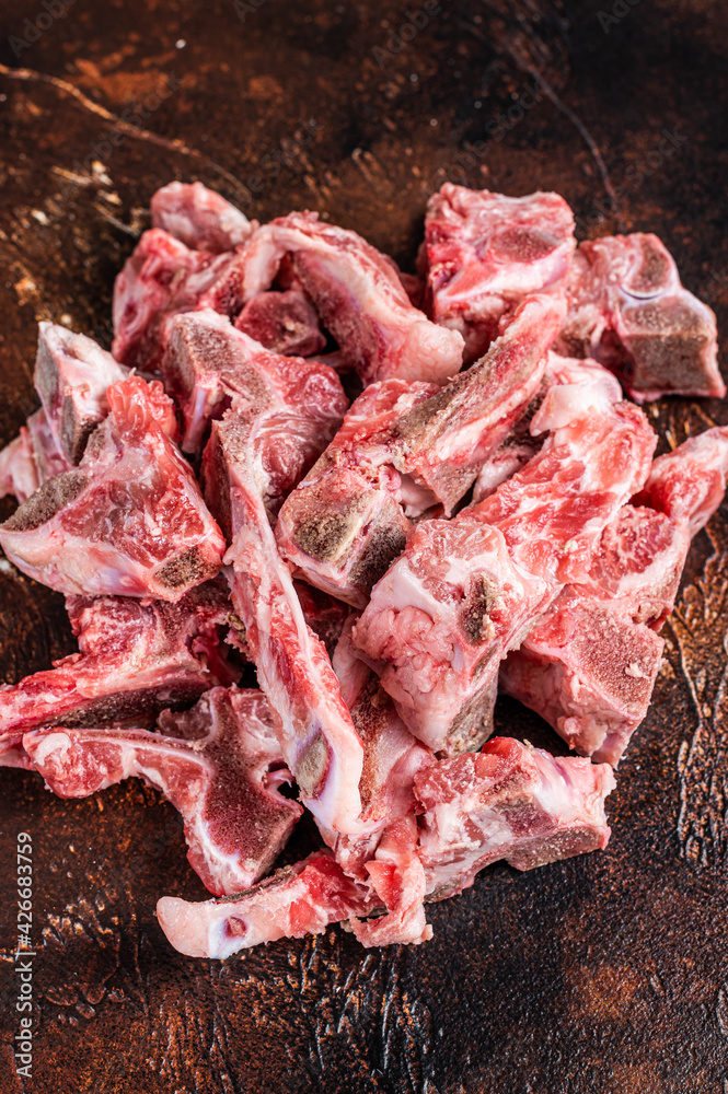 Raw meat on the bone diced for stew. Dark background. Top View