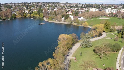 Cinematic aerial drone flyover shot of Green Lake Park with its running walking biking roller skating trail with nearby Wallingford, Woodland Park, Meridian, Phinney Ridge in Seattle, Washington photo