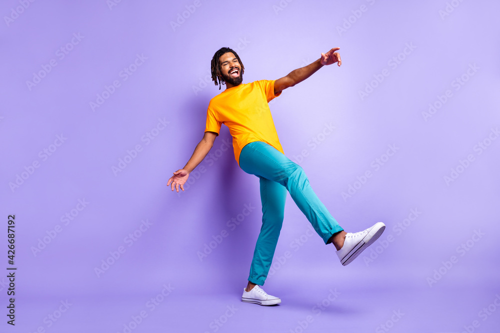 Full size photo of nice optimistic brunette hairdo guy dance wear orange t-shirt pants isolated on lilac color background
