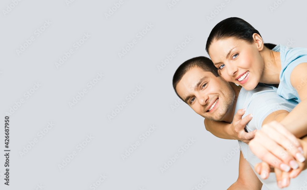 Happy amazed smiling couple. Portrait of standing close embracing models in blue casual clothing, love studio concept, grey color background. Young brunette man and woman posing together. Copy space.