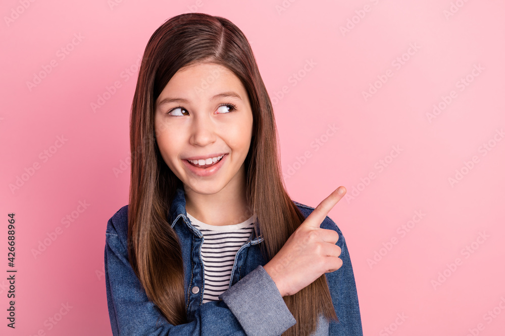 Photo portrait of small girl showing finger empty space dreamy isolated on pastel pink color background Photo portrait of small girl showing finger empty space dreamy isolated on pastel pink color background