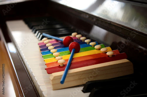 Close up image of a colorful toy xylophone with mallets put on the keyboard of a classical piano. photo