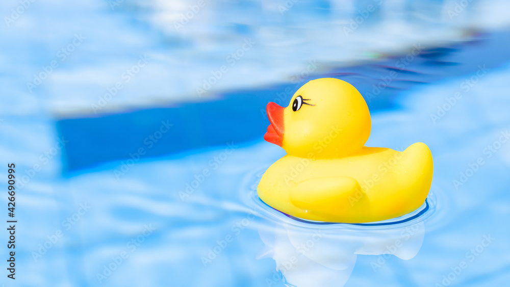 Kids rubber toy. Yellow inflatable duck for kids swim in blue water of summer pool. Trendy summer concept. Kids rubber toy. Yellow inflatable duck for kids swim in blue water of summer pool. Trendy summer concept.