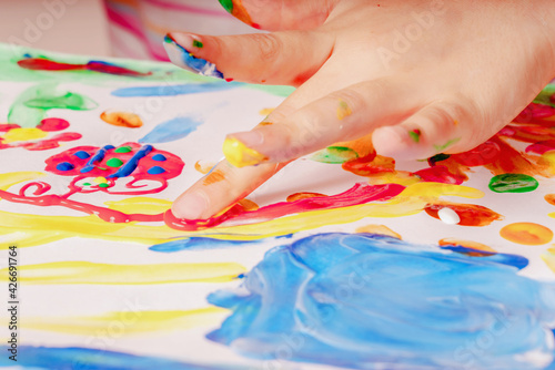 Close up young girl painting with colorful hands and fingers. Art, creativity and painting concept.