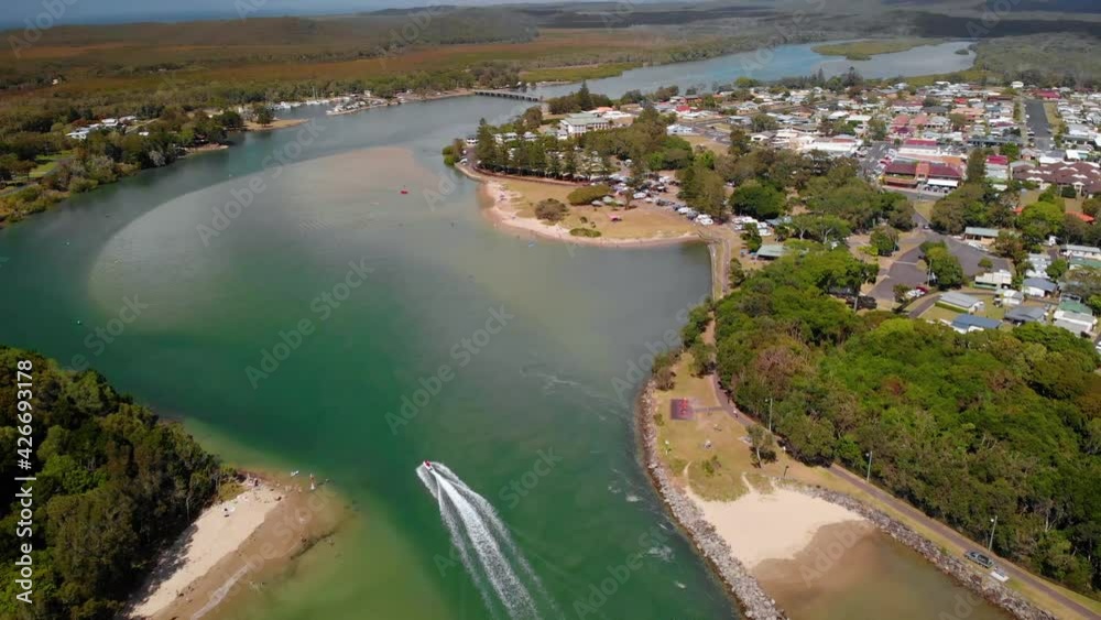 Aerial view of a boat on a river and the Evans Head town, New South Wales, Australia - tilt up, drone shot Aerial view of a boat on a river and the Evans Head town, New South Wales, Australia - tilt up, drone shot