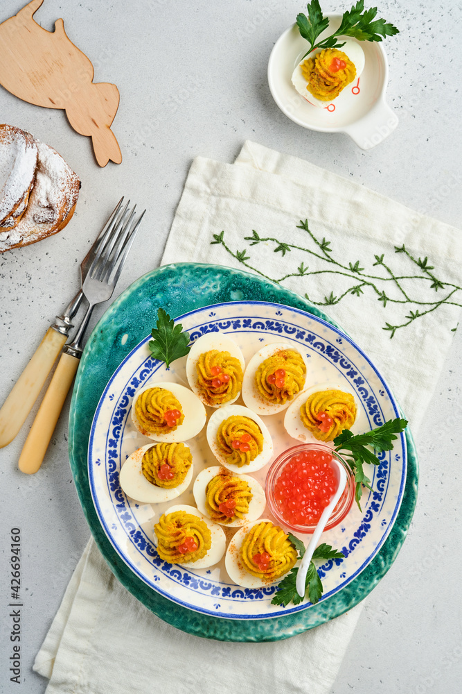 Stuffed eggs with red caviar and paprika on plate for appetizer easter table, top view, copy space. Traditional dish for Happy Easter holiday. Stuffed eggs with red caviar and paprika on plate for appetizer easter table, top view, copy space. Traditional dish for Happy Easter holiday.