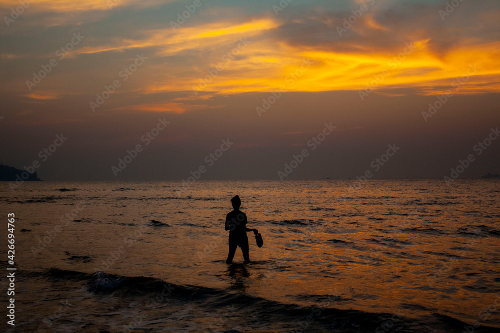 A silhouette with an Indian sunset over the water