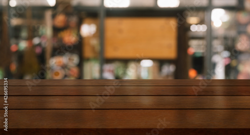 Empty wooden table top with lights bokeh on blur restaurant background.