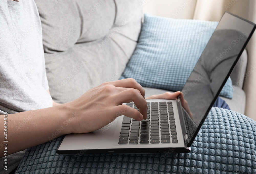 Hands typing by laptop at home on couch. Home office in lockdown time. Close up. Online education. Hands typing by laptop at home on couch. Home office in lockdown time. Close up. Online education.