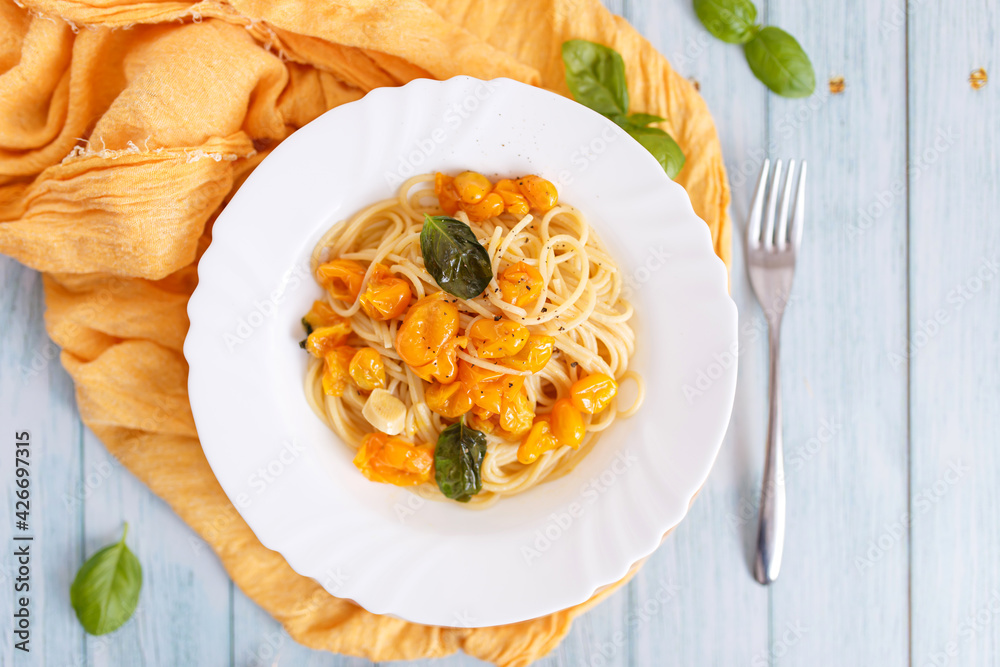 Pasta, spaghetti with yellow tomato in white plate. Blue background. Top view. Close up. Pasta, spaghetti with yellow tomato in white plate. Blue background. Top view. Close up.