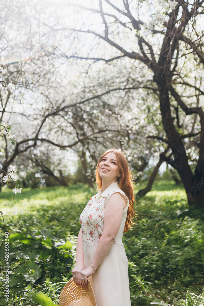 Red-haired girl walks in a spring blooming apple orchard Red-haired girl walks in a spring blooming apple orchard