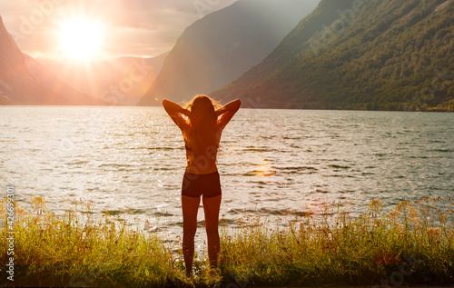 Frau am Ufer eines Bergsees bei Sonnenaufgang