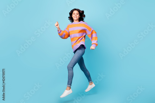 Full length body size view of lovely glad motivated fit cheerful wavy-haired girl jumping running action isolated over bright blue color background