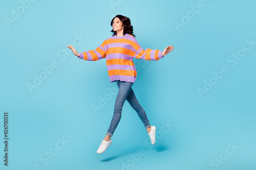 Full length body size view of pretty dreamy carefree fit cheerful wavy-haired girl jumping going isolated over bright blue color background