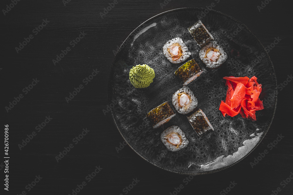 sushi roll with shrimp and rice in plate on black wooden table background