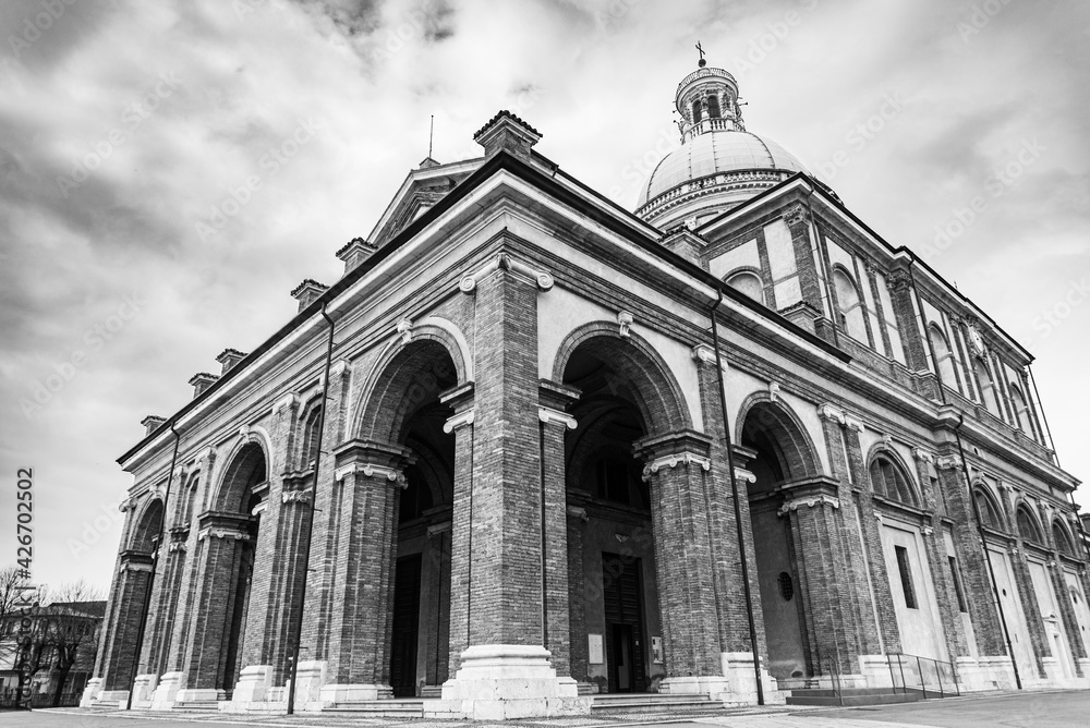 The famous ancient Caravaggio's Chatedral, Italy. View of the church from outside, with blue sky and white clouds on the background. Monochromatic.