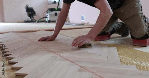 Laying parquet in an apartment during renovation. Herringbone parquet video 4k. Worker installing wood parquet.
