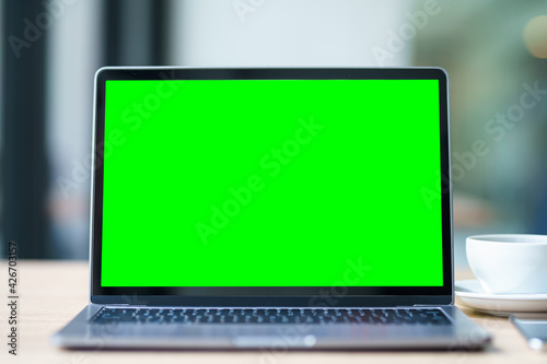 Obraz na płótnie Mockup of laptop computer with empty screen with coffee cup and smartphone on table of the coffee shop background,Green screen w salonie