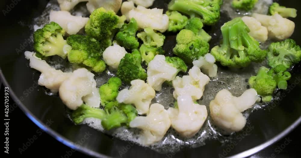 The fresh cut vegetables are fried on a frying pan, a cauliflower, broccoli, haricot, a bright and dietary dish, All this is fried on creamy oils, oil slowly bubbles, a healthy lifestyle The fresh cut vegetables are fried on a frying pan, a cauliflower, broccoli, haricot, a bright and dietary dish, All this is fried on creamy oils, oil slowly bubbles, a healthy lifestyle