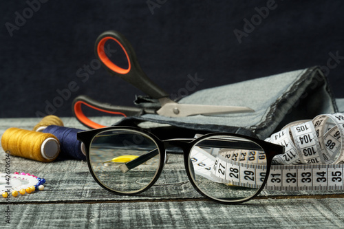 looking through glasses at sewing accessories. glasses for vision in black frames.