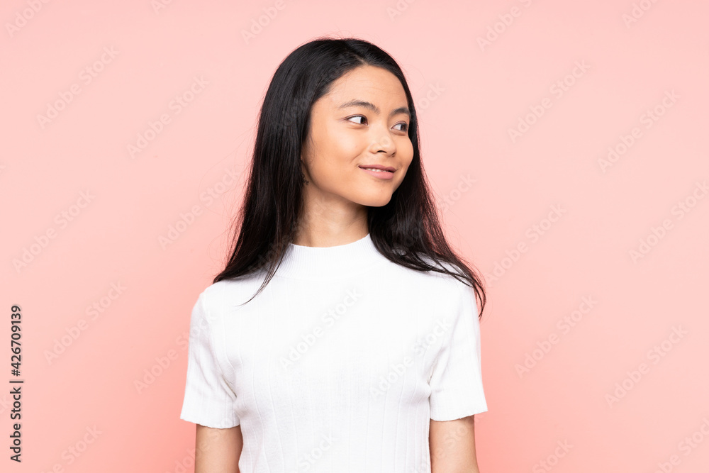 Teenager Chinese woman isolated on pink background looking to the side and smiling Teenager Chinese woman isolated on pink background looking to the side and smiling