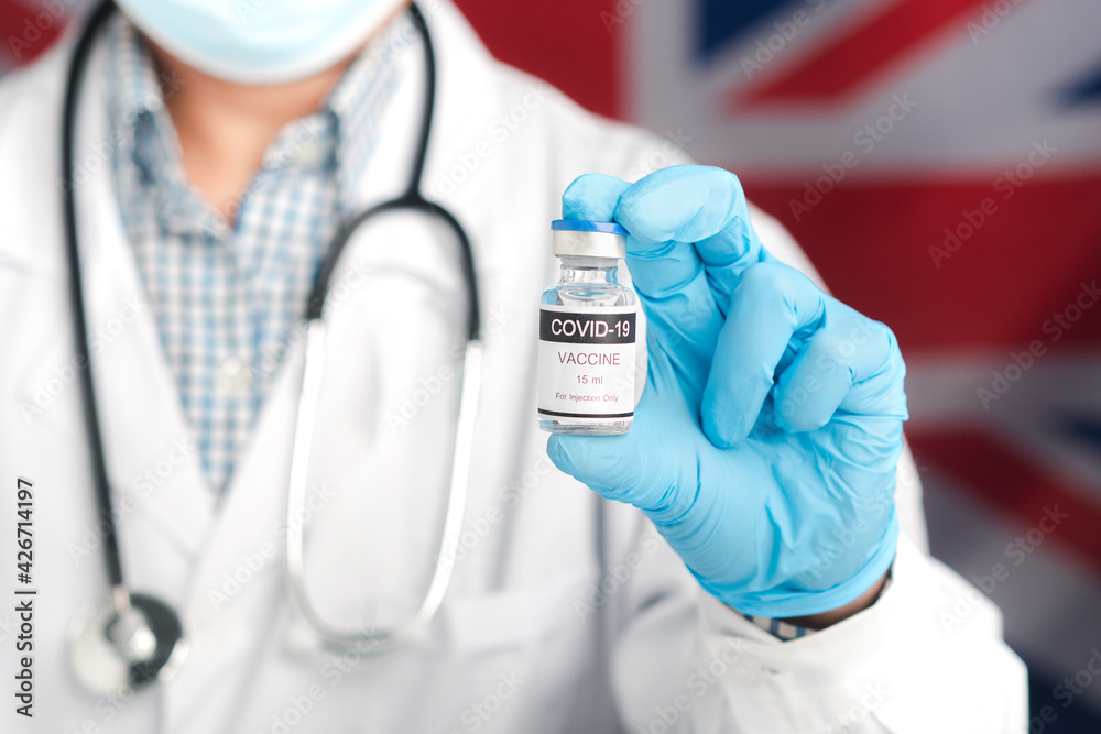A doctor holding a vaccine bottle with an England flag background. Vaccine for immunization, and treatment from virus infection. Concept of medical and the fight against the virus