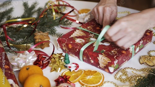 Women's hands tie a ribbon on a New Year's gift, New Year's decorations 4K