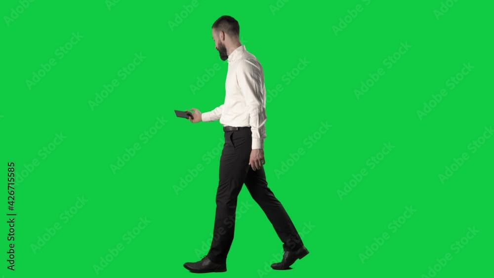 Side view of walking business man photographing or filming videos with smart phone. Full body on green screen chroma key background. Side view of walking business man photographing or filming videos with smart phone. Full body on green screen chroma key background.