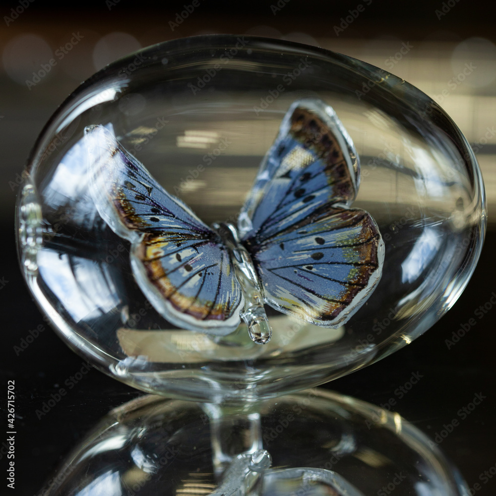 glass Easter egg with a butterfly inside on a silver background. glass egg. butterfly close up