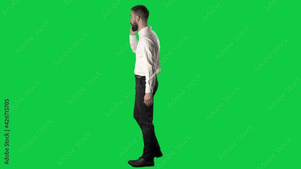 Side view of walking happy confident business man answer call and talking on the phone. Full body on green screen chroma key background. Side view of walking happy confident business man answer call and talking on the phone. Full body on green screen chroma key background.