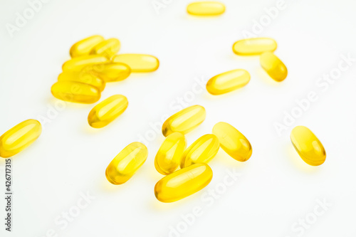 Golden capsules of pills poured from a jar on a white background. Medicines for treatment. Fish oil, omega-3