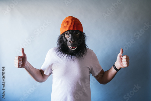 Male in a chimpanzee mask gesturing the like sign with both hands photo