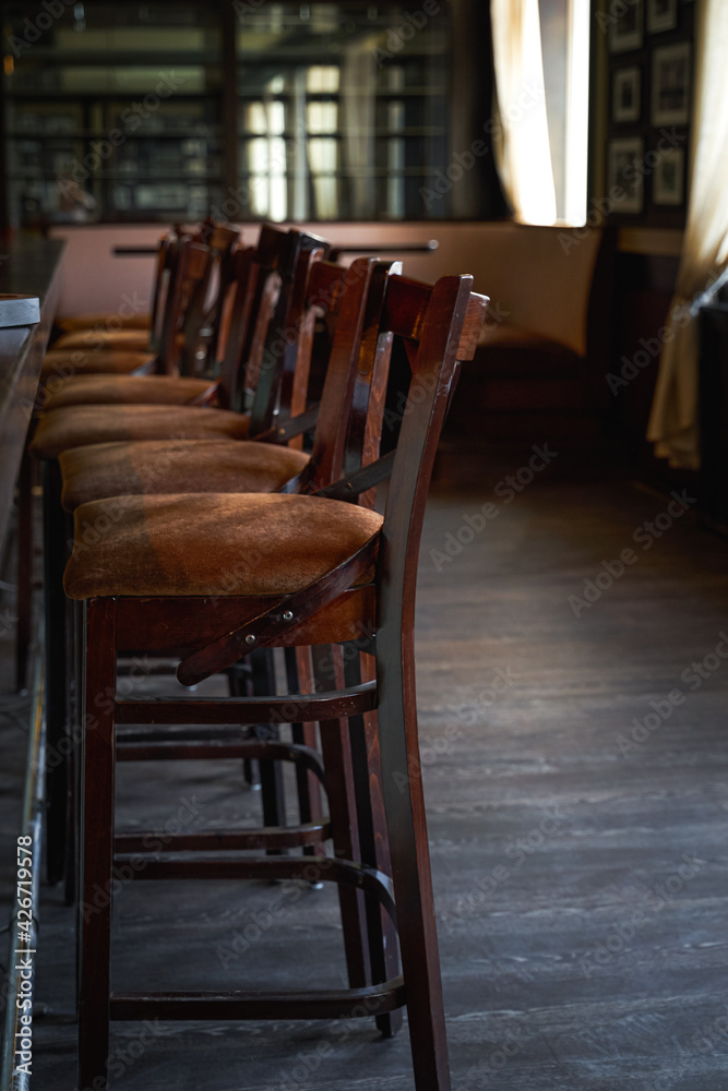 Wooden chairs beside bar counter in a row. Empty cafe in the morning Wooden chairs beside bar counter in a row. Empty cafe in the morning