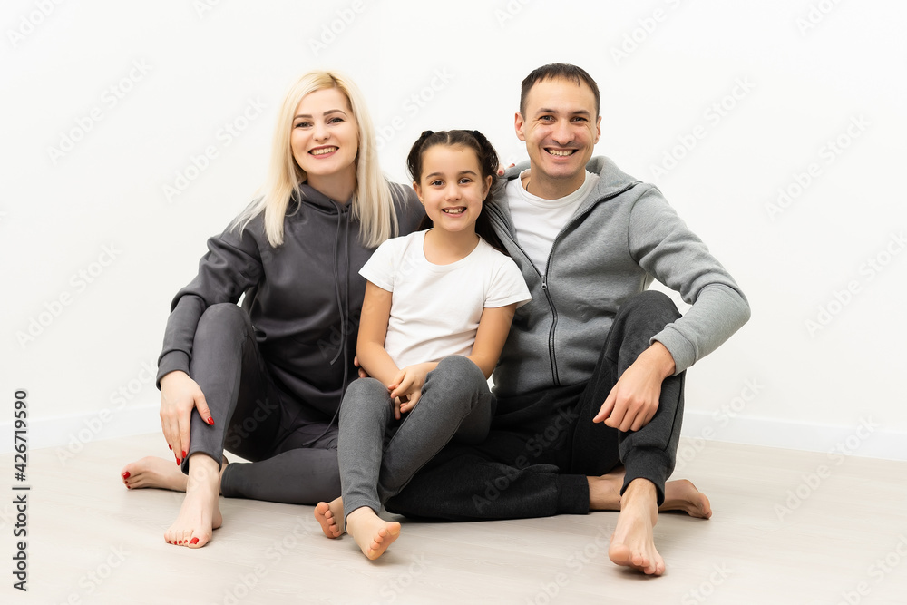 Photo of adorable caucasian family woman and man with little girl smiling and posing together at camera over white background Photo of adorable caucasian family woman and man with little girl smiling and posing together at camera over white background