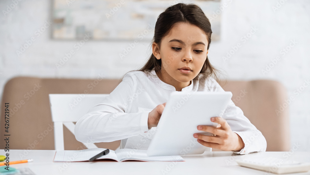 Girl using digital tablet near notebook and blurred calculator. Girl using digital tablet near notebook and blurred calculator.