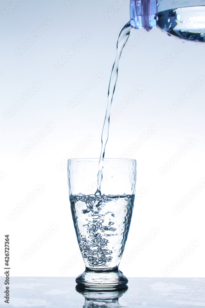 Pour the water from the bottle into the glass Pour the water from the bottle into the glass