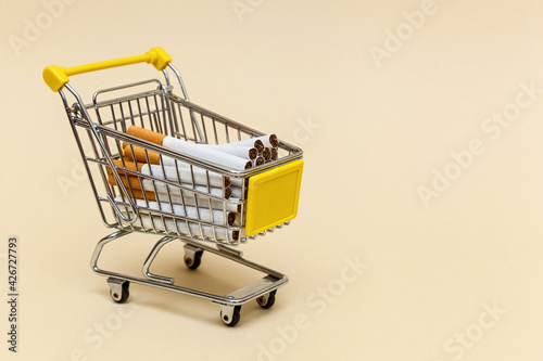 Metal shopping cart on a beige background.