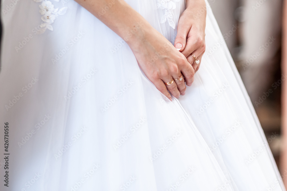 Hands of the bride on a white dress
