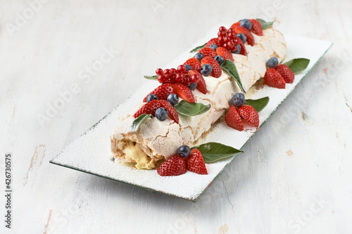 Meringue roll Pavlova cake with cream and raspberries, blackberries and blueberries